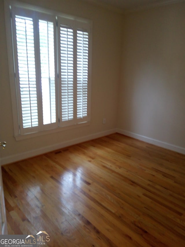 empty room featuring hardwood / wood-style flooring and ornamental molding