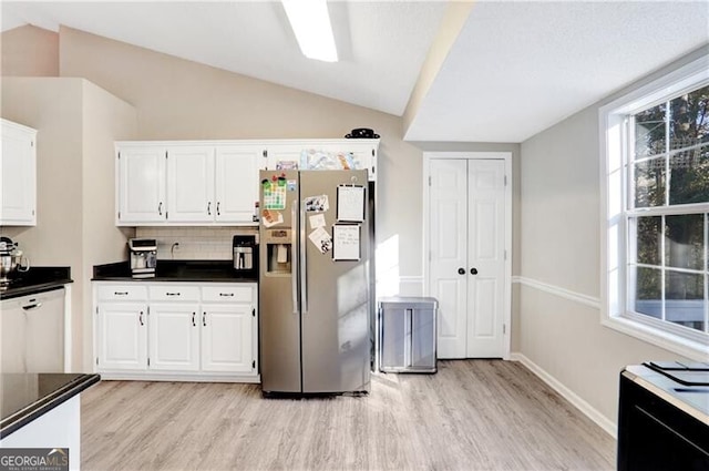 kitchen with vaulted ceiling, white cabinets, light hardwood / wood-style floors, and stainless steel refrigerator with ice dispenser