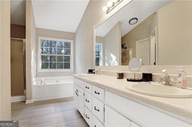 bathroom featuring vanity, independent shower and bath, and vaulted ceiling