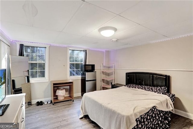 bedroom with light hardwood / wood-style floors and stainless steel refrigerator