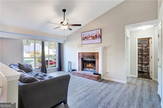 living room with a brick fireplace, hardwood / wood-style flooring, vaulted ceiling, and ceiling fan