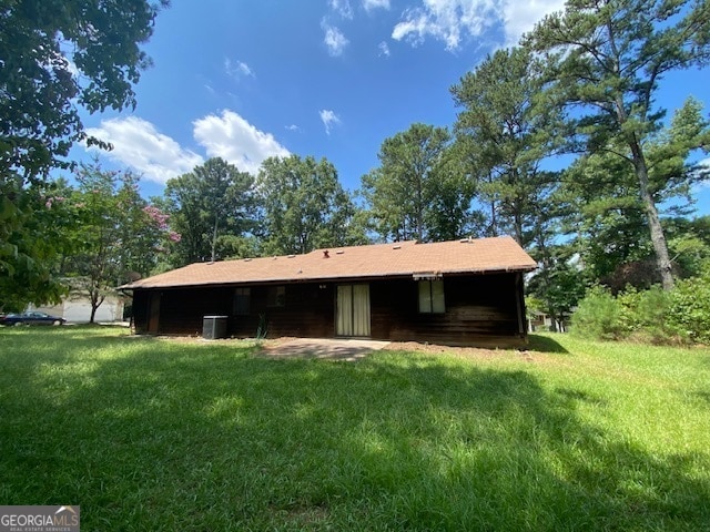 back of house with central AC unit and a yard