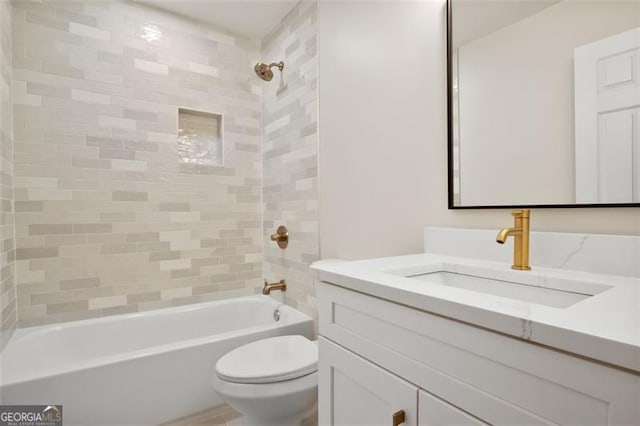 full bathroom with vanity, tiled shower / bath, and toilet