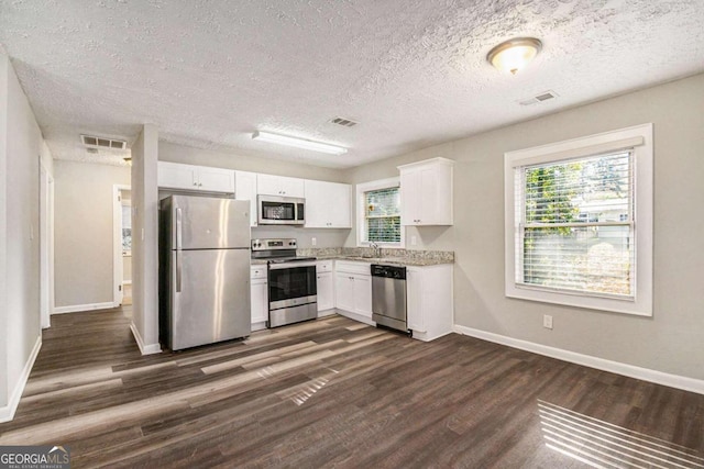 kitchen with sink, dark wood-type flooring, a textured ceiling, white cabinets, and appliances with stainless steel finishes