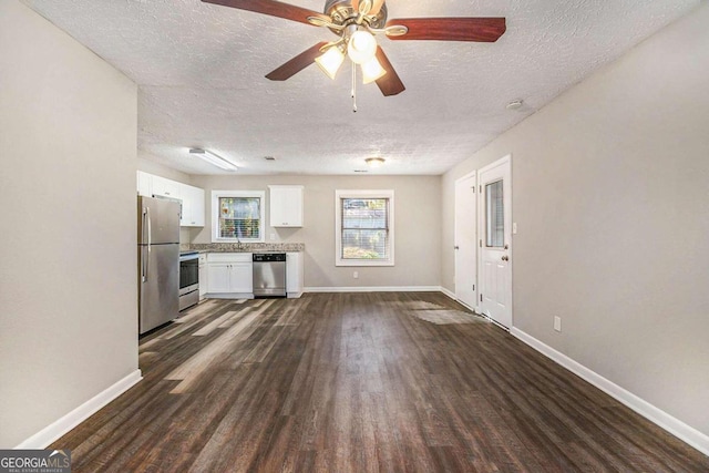 unfurnished living room featuring dark hardwood / wood-style floors, ceiling fan, sink, and a textured ceiling