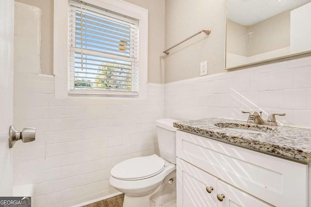 bathroom featuring vanity, toilet, and tile walls