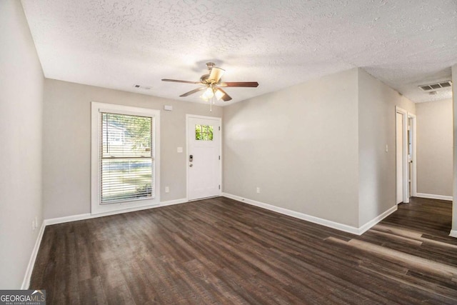 empty room with ceiling fan, dark wood-type flooring, and a textured ceiling