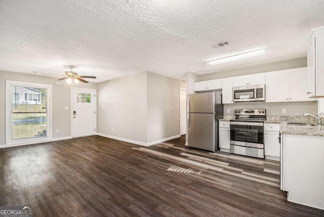 kitchen with appliances with stainless steel finishes, dark hardwood / wood-style flooring, a textured ceiling, sink, and white cabinets