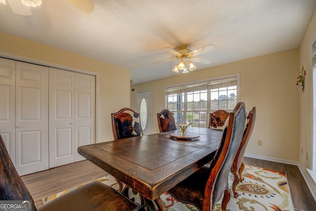 dining space with ceiling fan, dark hardwood / wood-style flooring, and a textured ceiling