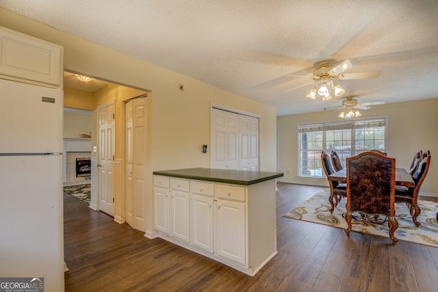 kitchen with ceiling fan, white fridge, white cabinetry, and dark hardwood / wood-style floors