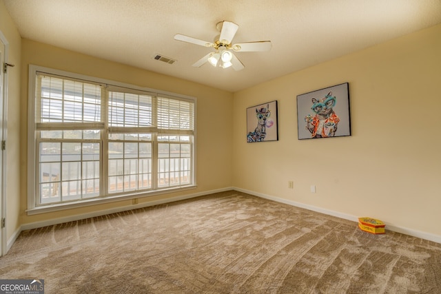 spare room with a textured ceiling, carpet floors, and ceiling fan