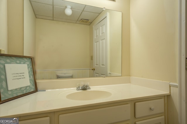 bathroom featuring a drop ceiling, vanity, and toilet