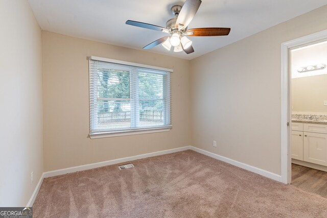 unfurnished bedroom with connected bathroom, light colored carpet, and ceiling fan