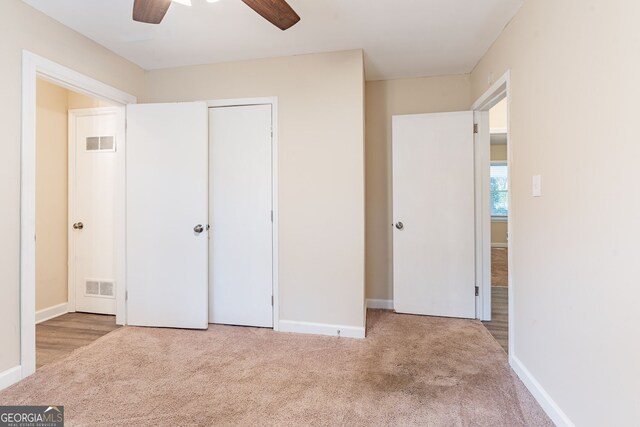 unfurnished bedroom featuring ceiling fan, light carpet, and a closet