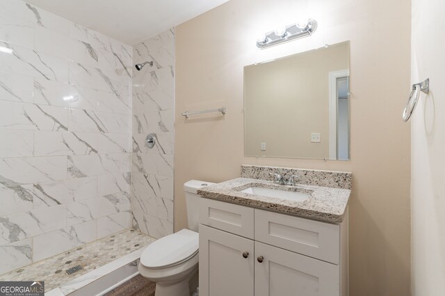 bathroom with tiled shower, vanity, and toilet