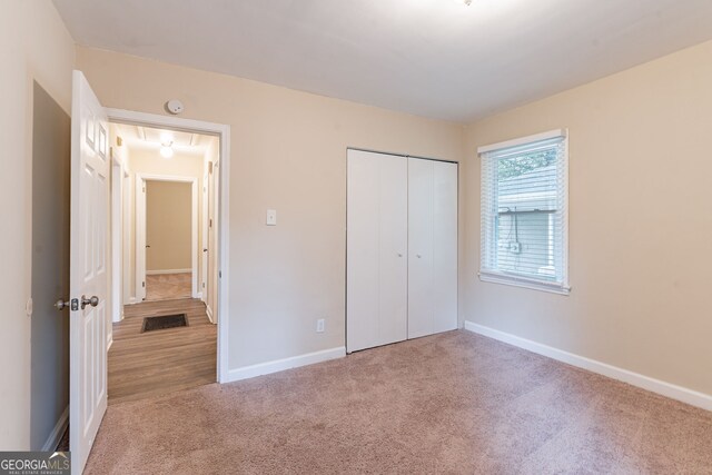 unfurnished bedroom with light colored carpet and a closet