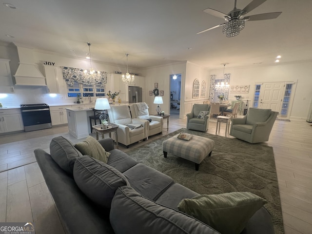 living room with sink, ceiling fan with notable chandelier, and light wood-type flooring