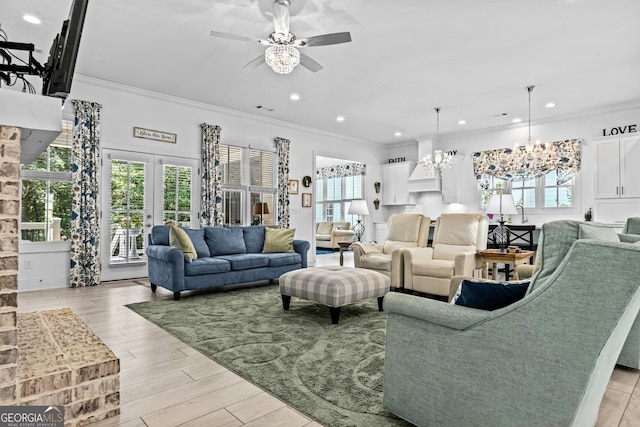 living room featuring crown molding, ceiling fan with notable chandelier, and french doors