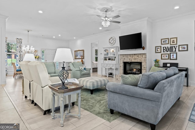 living room featuring crown molding, ceiling fan with notable chandelier, and a brick fireplace