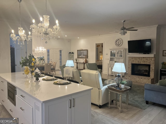 kitchen featuring stainless steel microwave, a kitchen island, pendant lighting, ceiling fan, and white cabinets