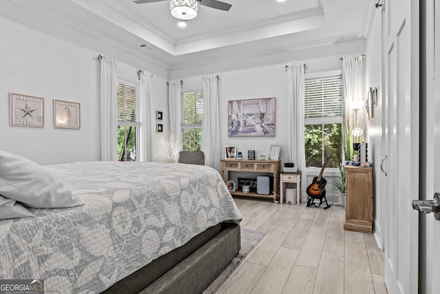 bedroom with multiple windows, a tray ceiling, and ceiling fan