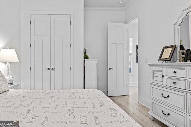 bedroom with light hardwood / wood-style flooring, ornamental molding, and a closet