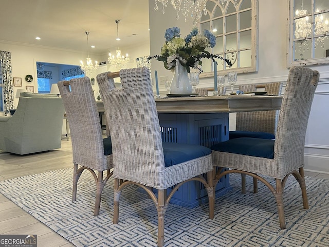 dining room with an inviting chandelier, ornamental molding, and light wood-type flooring