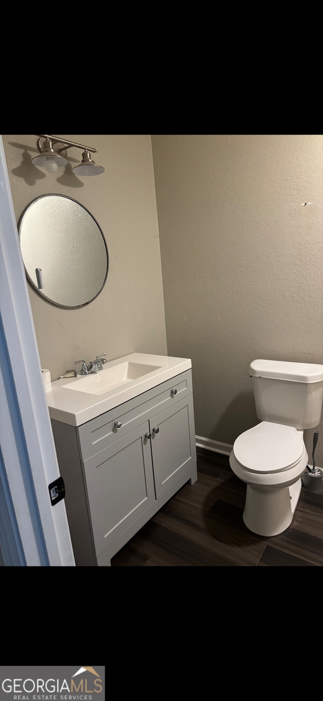 bathroom with hardwood / wood-style floors, vanity, and toilet