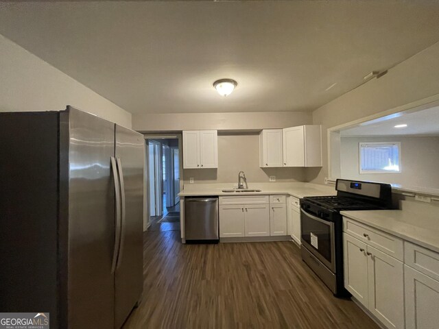 kitchen with stainless steel appliances, white cabinetry, dark wood-type flooring, and sink