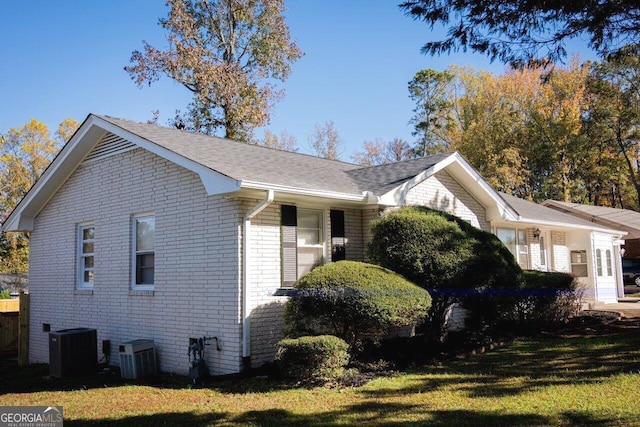 view of side of home with a lawn and central air condition unit