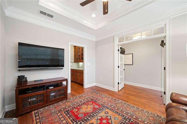 living room featuring hardwood / wood-style floors, ceiling fan, and ornamental molding