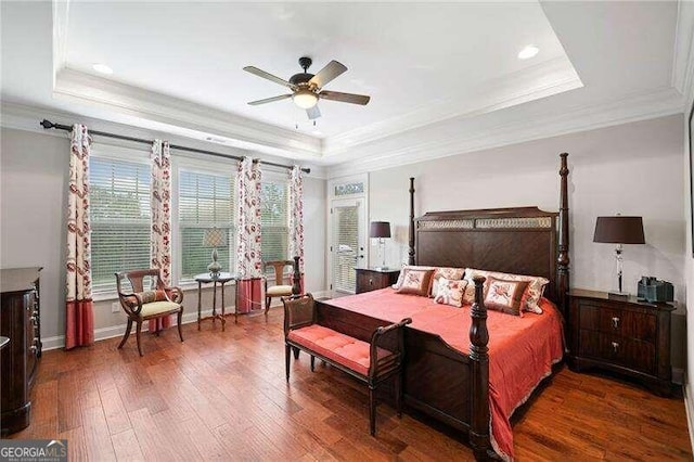 bedroom with ceiling fan, dark hardwood / wood-style floors, ornamental molding, and a tray ceiling