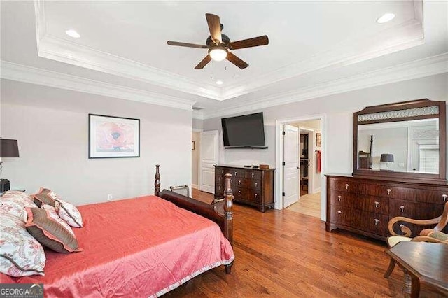 bedroom featuring ceiling fan, light hardwood / wood-style floors, crown molding, and a tray ceiling