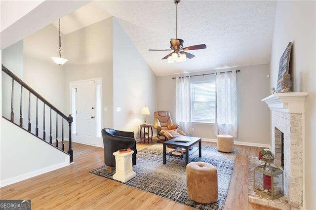 living room featuring hardwood / wood-style floors, a textured ceiling, high vaulted ceiling, and ceiling fan