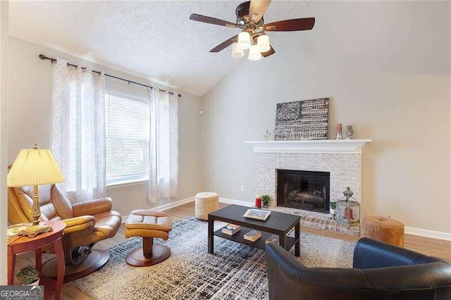 living room featuring lofted ceiling, hardwood / wood-style flooring, ceiling fan, a textured ceiling, and a fireplace