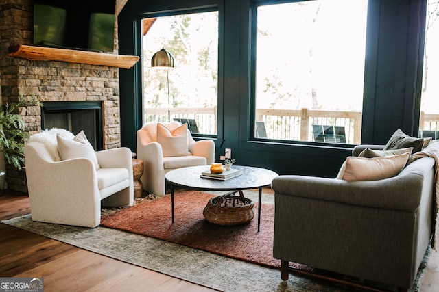 living area with a stone fireplace and wood-type flooring