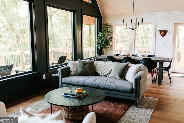 interior space featuring an inviting chandelier, vaulted ceiling, and hardwood / wood-style flooring