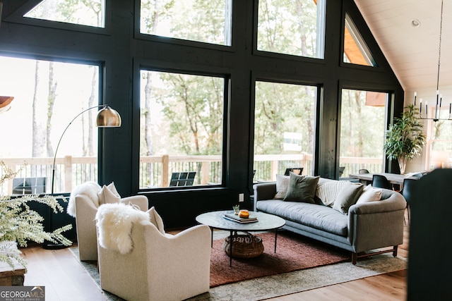 living room featuring high vaulted ceiling, light hardwood / wood-style floors, and a wealth of natural light