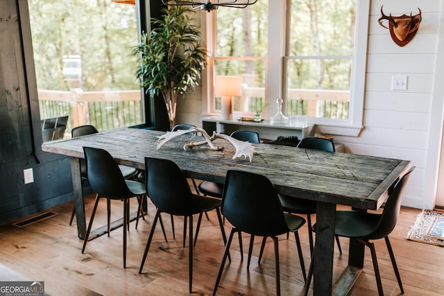 dining area featuring light hardwood / wood-style floors and wooden walls