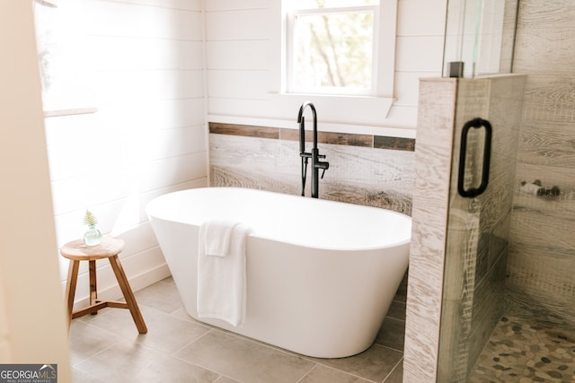 bathroom featuring tile patterned flooring, tile walls, and independent shower and bath