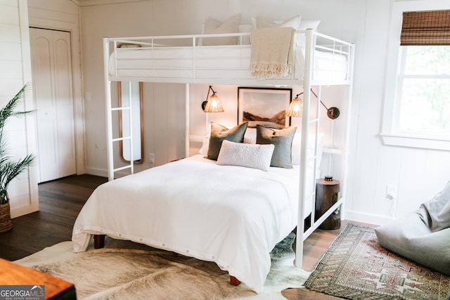 bedroom with dark hardwood / wood-style flooring and wooden walls