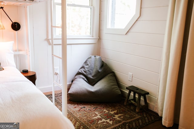 bedroom with wood-type flooring and wooden walls