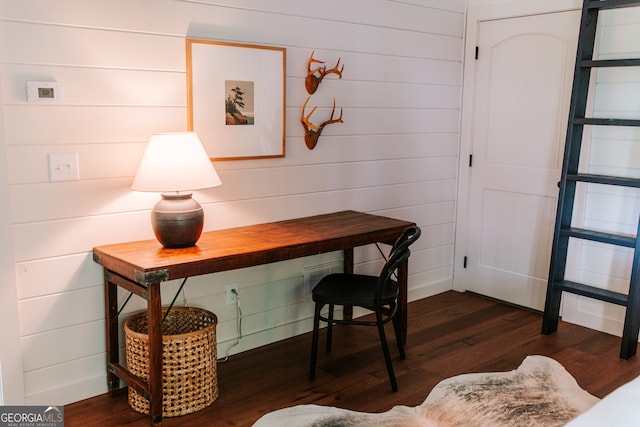 home office with dark hardwood / wood-style floors and wood walls