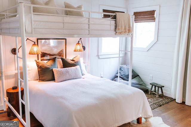 bedroom with wood walls and wood-type flooring