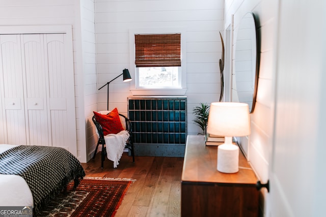 bedroom featuring hardwood / wood-style floors, wood walls, and a closet