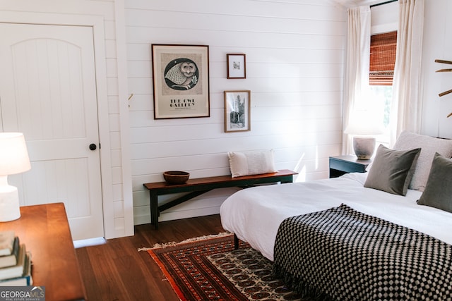 bedroom featuring dark hardwood / wood-style flooring and wooden walls