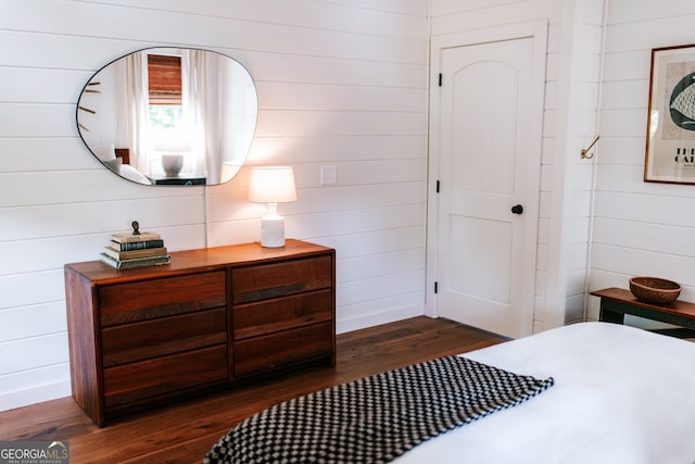 bedroom with wooden walls and dark hardwood / wood-style flooring