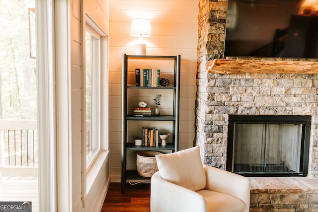 living area featuring dark hardwood / wood-style floors and a stone fireplace