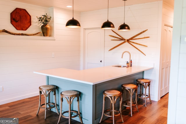 kitchen featuring hardwood / wood-style floors, decorative light fixtures, a kitchen breakfast bar, and sink