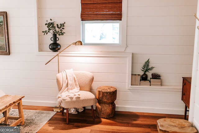 sitting room featuring wood-type flooring and wooden walls